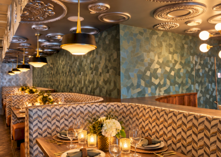 A cozy dining area with a wooden table set for meals and ornate ceiling lamps under blue patterned walls.